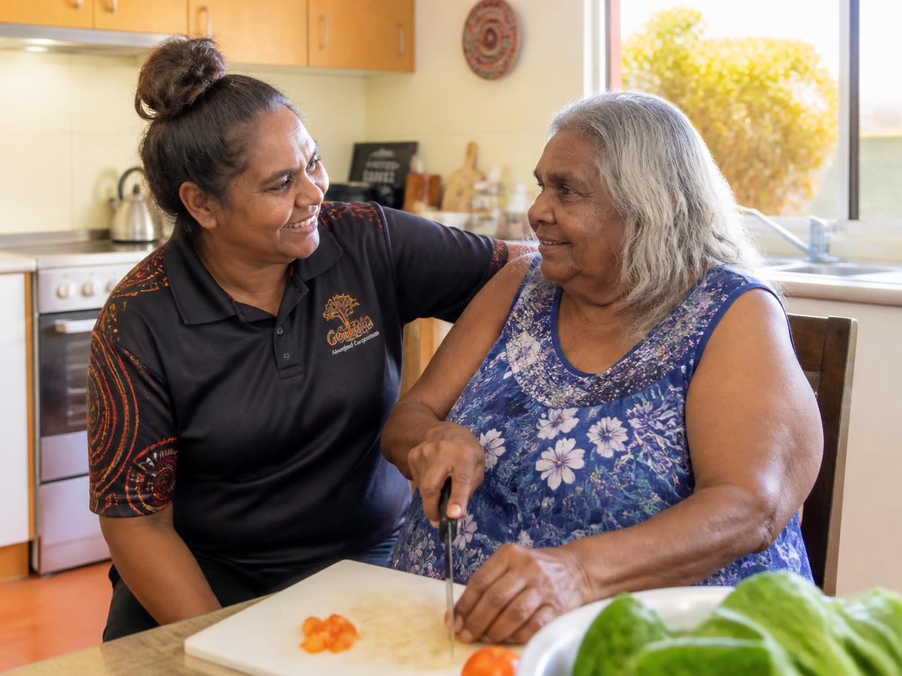 An Aboriginal support worker helping an Elder prepare a meal in her kitchen